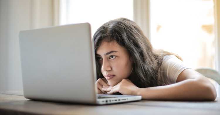 A bored student works at a computer, displaying the struggles students face with personalized learning.